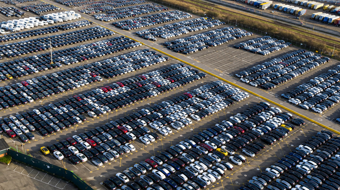 Aerial view of a large parking lot filled with rows of parked cars arranged neatly.